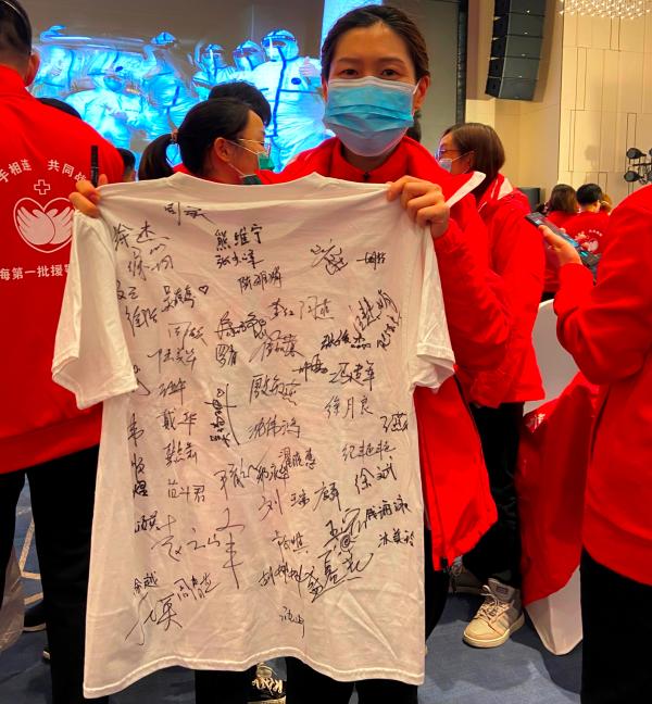 送别仪式现场，队员们拿着T恤和象征“战袍”的洁净防护服让其他队员们挨个签名。 澎湃新闻记者 赵思维 图